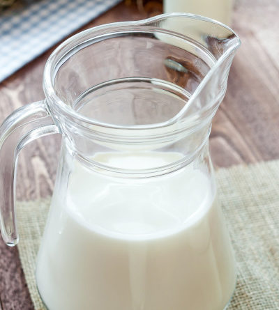 Milch in einer Kanne und mehrere Gläser gefüllt mit Milch.