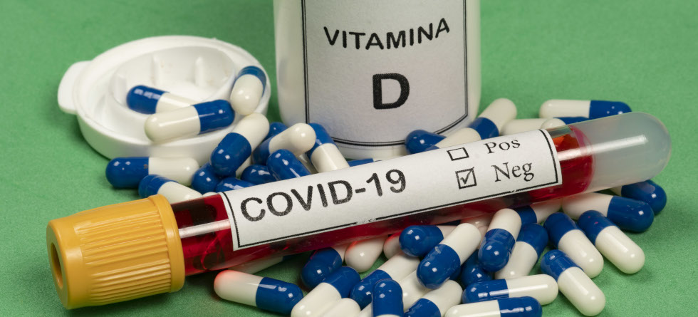 Vitamin-D-Kapseln und Vakuumröhrchen mit der Aufschrift COVID-19