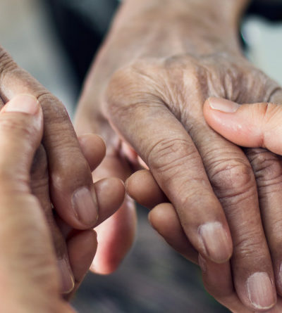 Nahaufnahme: Eine jüngere Person hält die Hände von einer älteren Person.