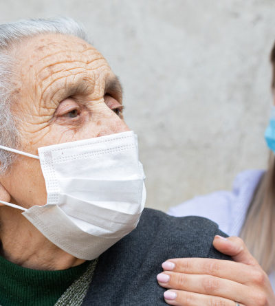 Seniorin und Krankenpflegerin mit OP-Masken