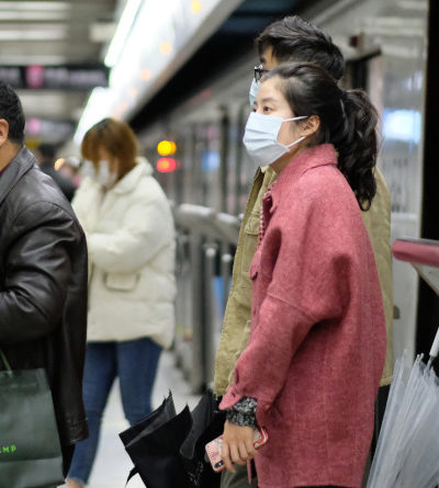 Menschen, die eine OP-Maske tragen, gehen aus der U-Bahn in Shanghai.