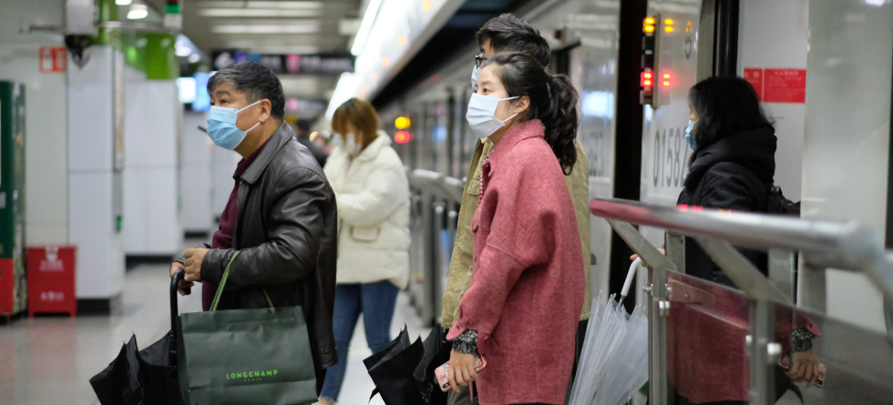 Menschen, die eine OP-Maske tragen, gehen aus der U-Bahn in Shanghai.