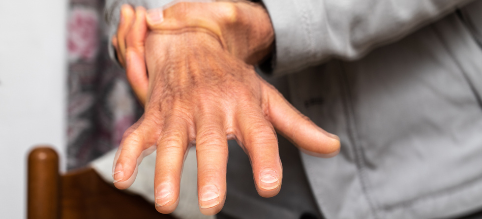 Nahaufnahme der Hand einer älteren Person. Verschwommenes Bild soll zeigen, dass die Hand stark zittert.