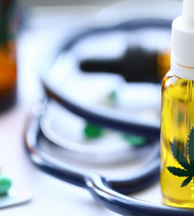 Cannabis-Öl und Tabletten sowie ein Stethoskop liegen auf einem Tisch.