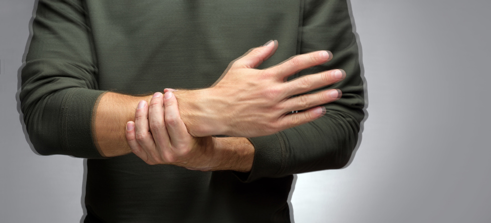 Person mit Tremor hält mit der Hand seinen Arm fest.