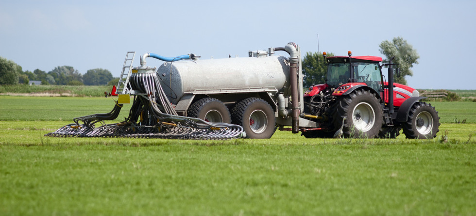 Landwirtschaftliches Fahrzeug düngt ein Feld.