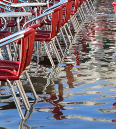 Stühle und Tische stehen auf einem überschwemmten Platz.