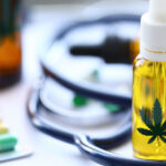 Cannabis-Öl und Tabletten sowie ein Stethoskop liegen auf einem Tisch.